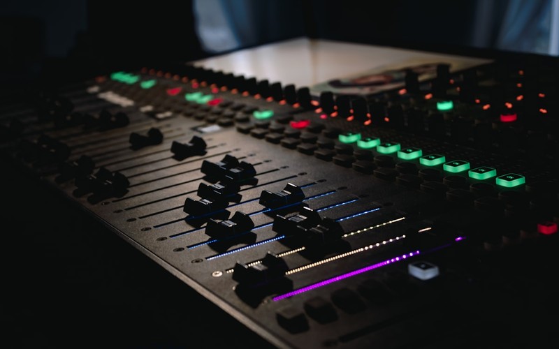 Close-up of a professional mixing console in a recording studio with illuminated controls