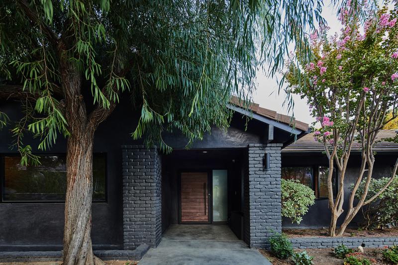 Modern luxury home entrance with black brick pillars and lush landscaping in Bell Canyon gated community