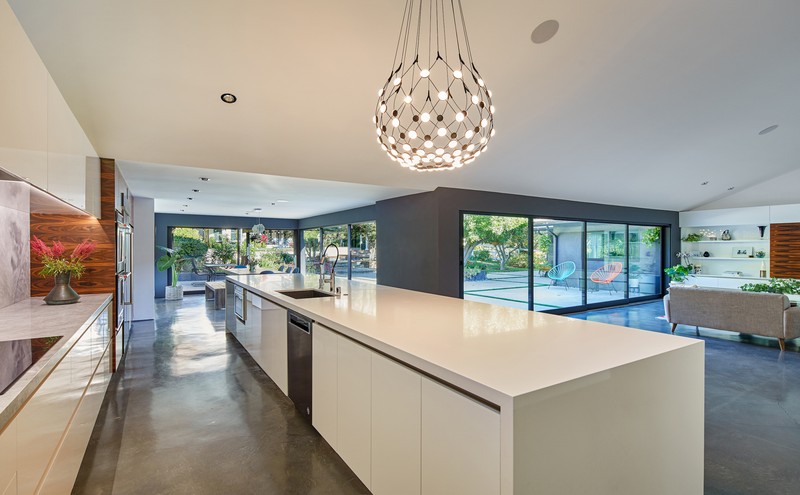 Modern luxury kitchen with central island, spherical chandelier, and open-to-outdoor design