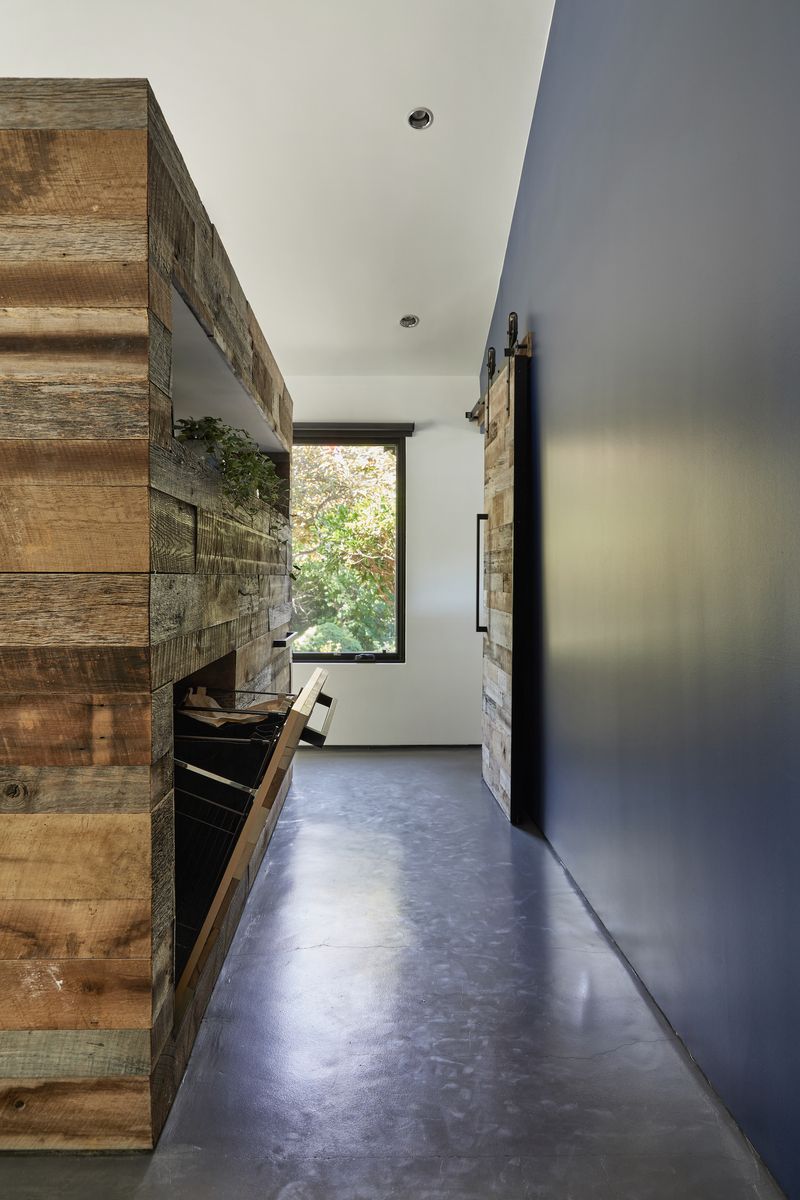 Sleek modern hallway featuring a reclaimed wood accent wall, barn door, and polished concrete floor