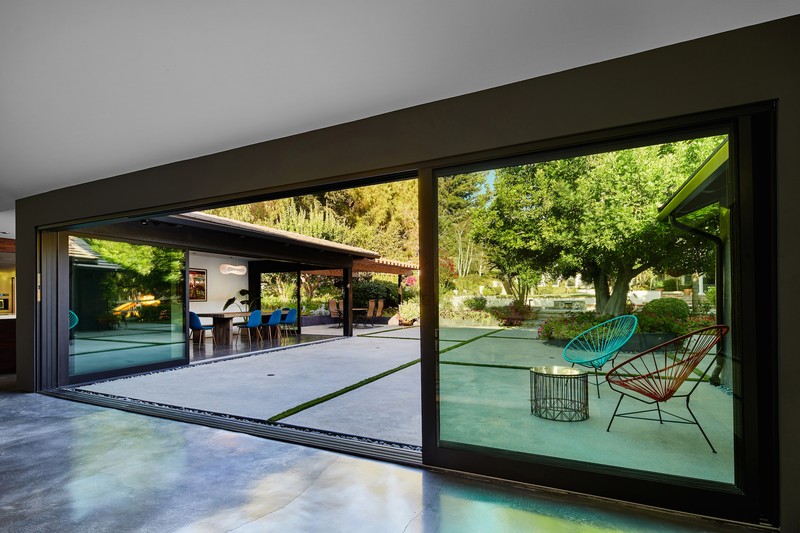 Sleek modern indoor-outdoor living space with glass sliding doors opening to a lush garden