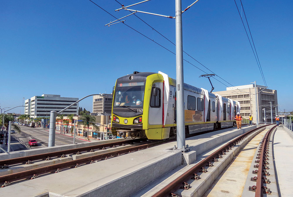 Los Angeles Metro light rail train on elevated tracks serving South LA neighborhoods along the Crenshaw LAX transit corridor