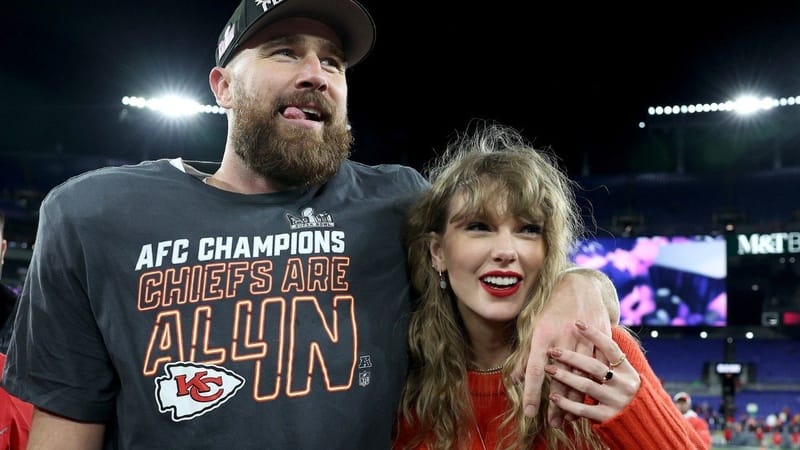 Travis Kelce and Taylor Swift pose together at a stadium during an AFC Championship event