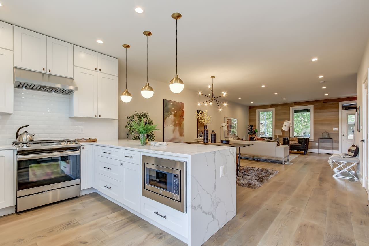 A freshly remodeled modern kitchen featuring an open-concept layout, an integrated center island with quartz countertops, and updated vertical storage cabinets.